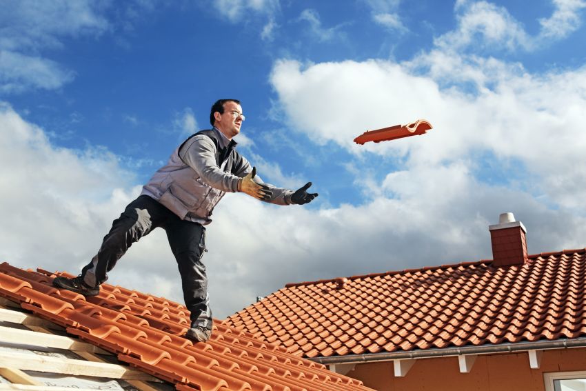 Dachdecker auf Dach wirft Ziegel