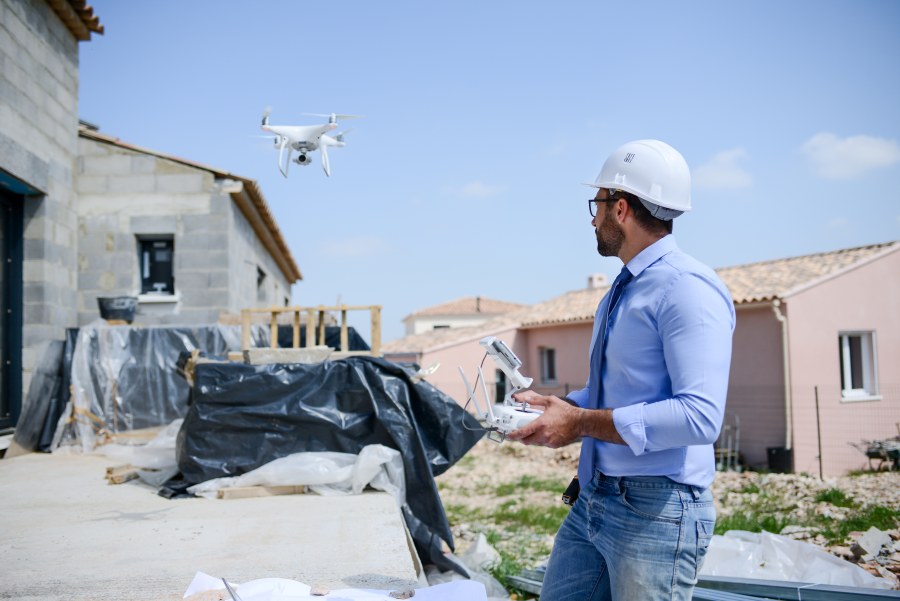 Drohnenpilot steuert Drohne über Neubau