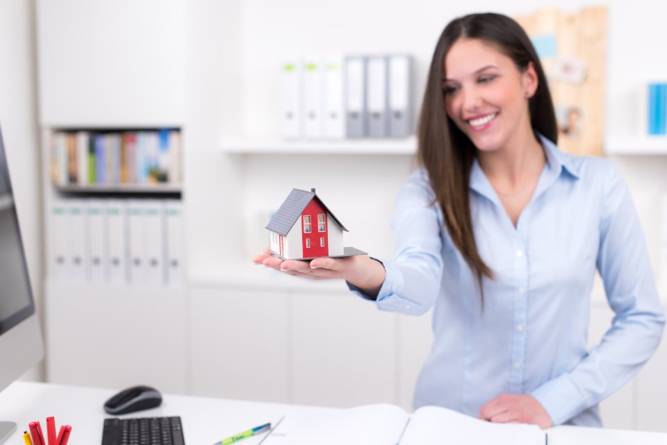 Verkäuferin hat Modellhaus in der Hand