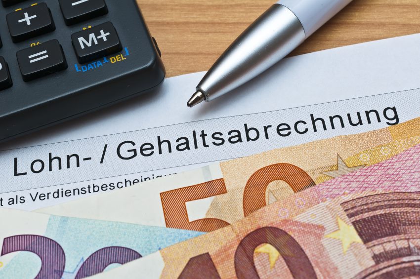 Gehaltsabrechnung mit Geld, Kugelschreiber und Taschenrechner