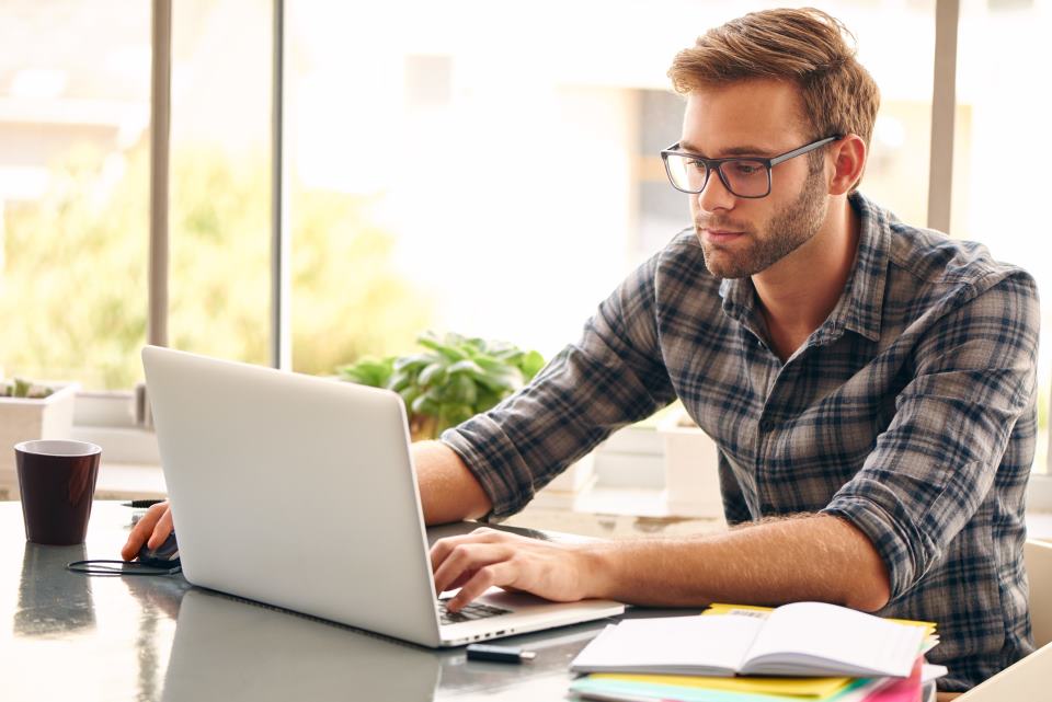 junger Mann am Schreibtisch mit Notebook