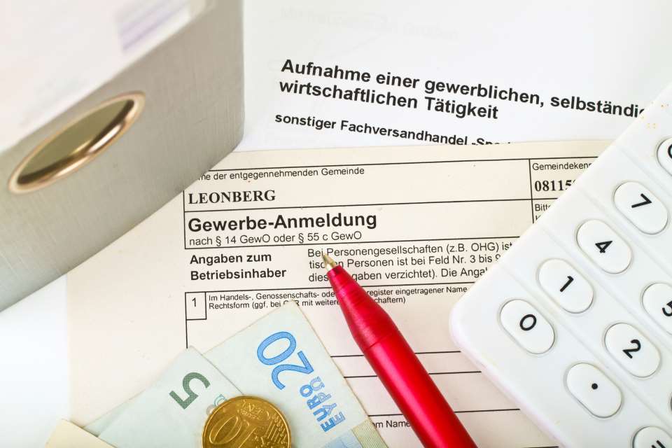 Gewerbeformular mit Geld, Kugelschreiber und Taschenrechner