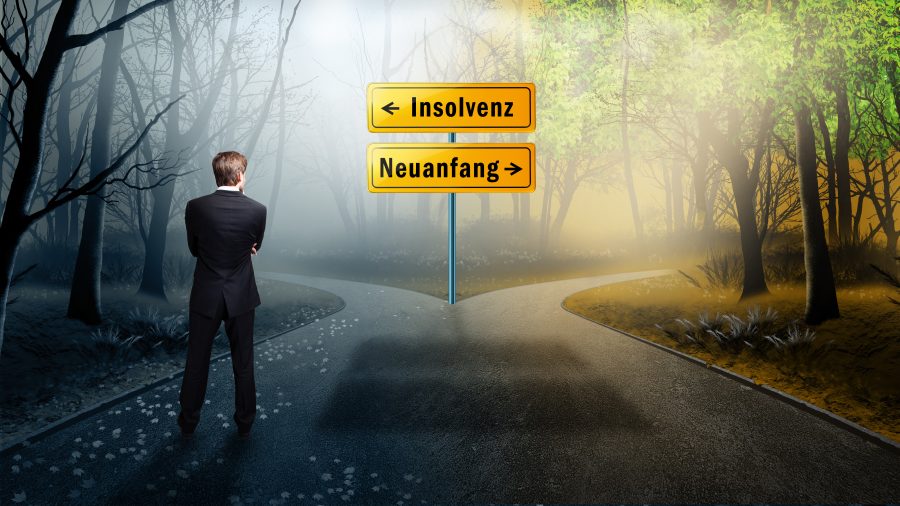 Geschäftsmann steht vor Schild Insolvenz Neustart