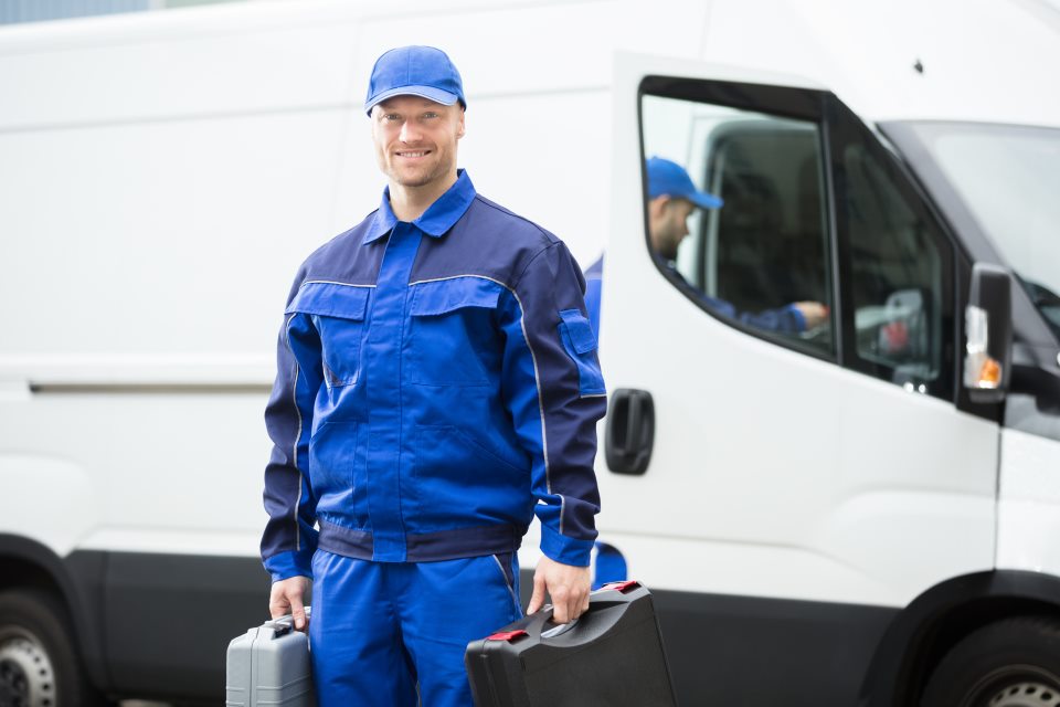 Handwerker mit Koffer vor Lieferwagen