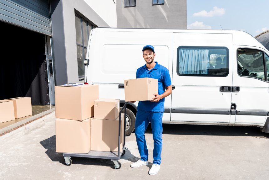 Lieferant mit Paket vor Lieferwagen