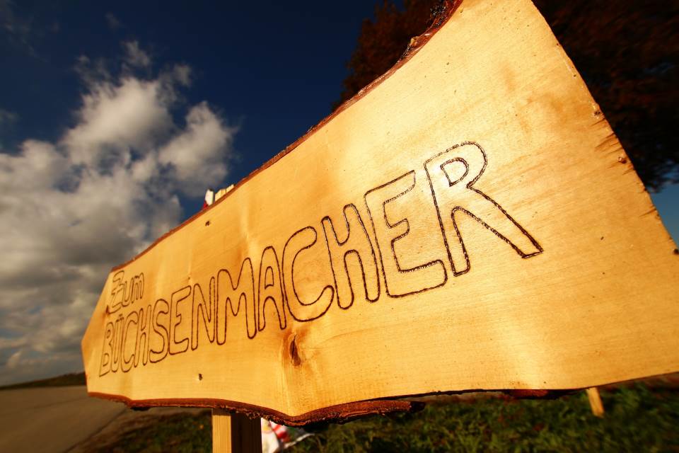 Holzschild mit Aufschrift "zum Büchsenmacher"