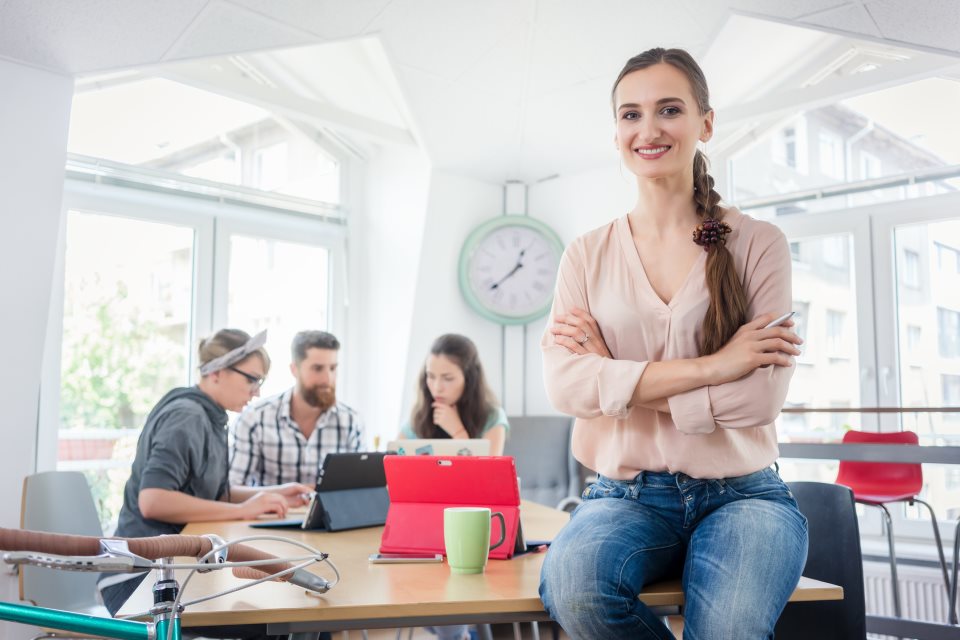 Startup Gründerin vor Kollegen am Schreibtisch