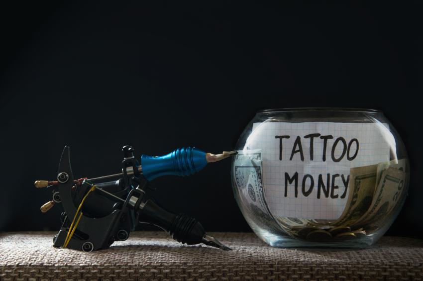 Tattoonadel neben Glas mit Geld